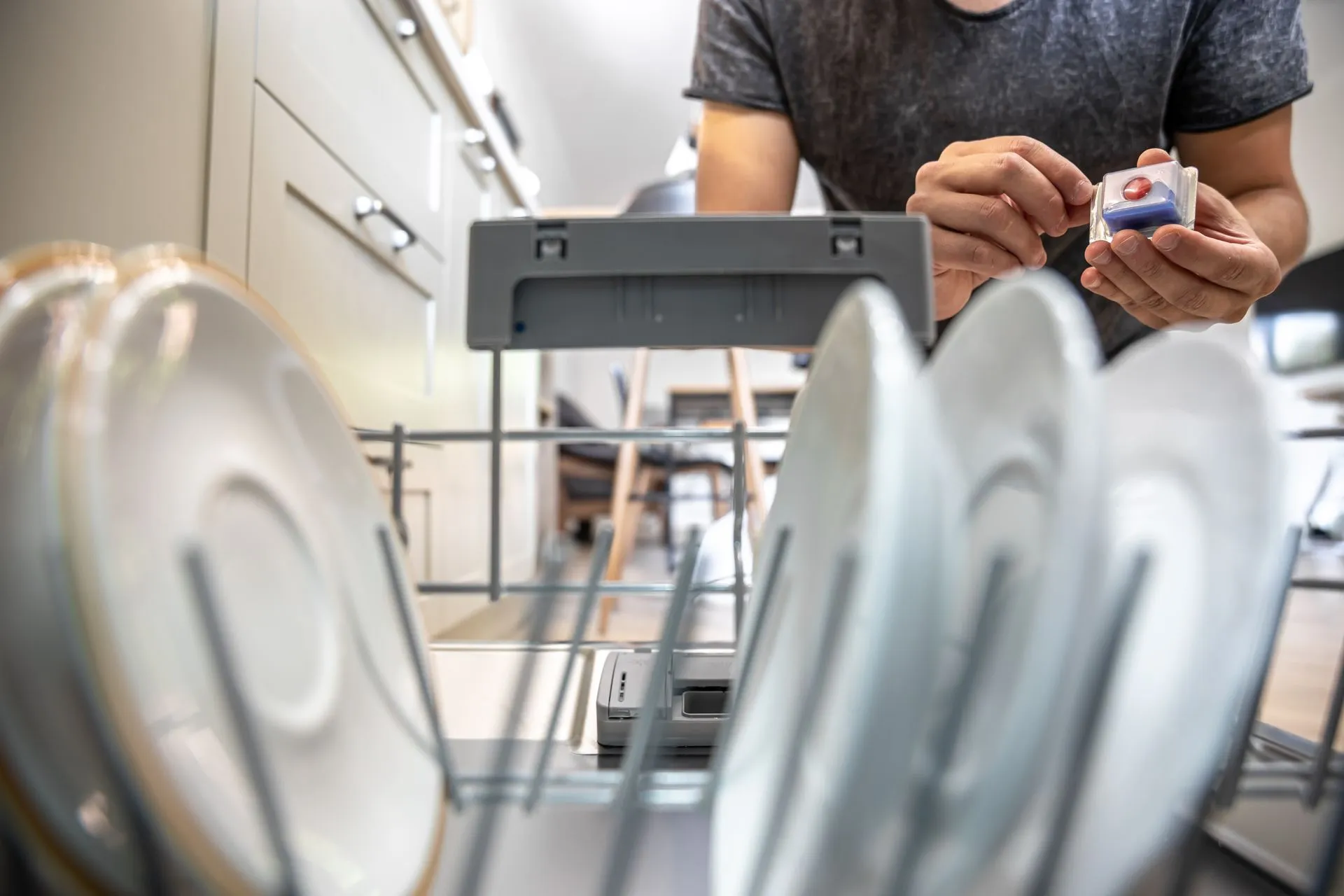 Homeowner loading a detergent pod into an open dishwasher